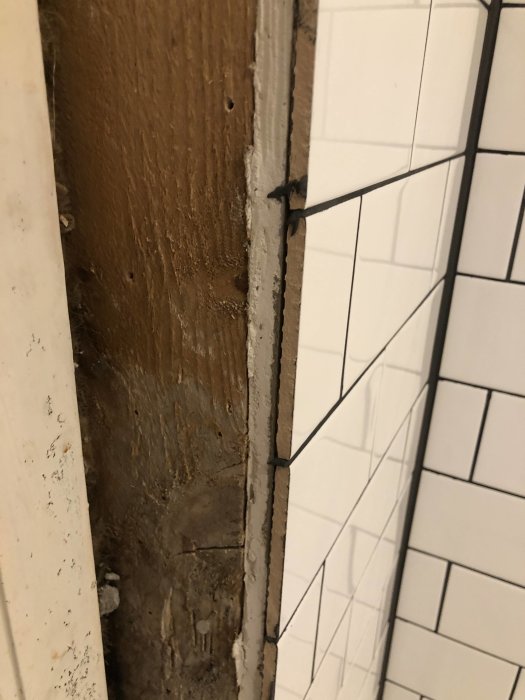 Golvbrunn med rött tätskikt och grått kakellim runt klinkerramen, otillräcklig väggtätning vid brunnen.