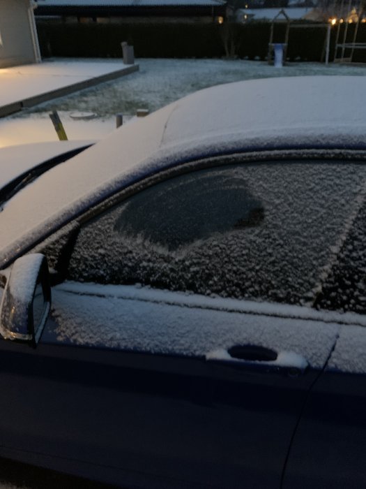 Bil täckt med snö framför hus med insyn till olåst bil som kan övervakas av en säkerhetskamera.