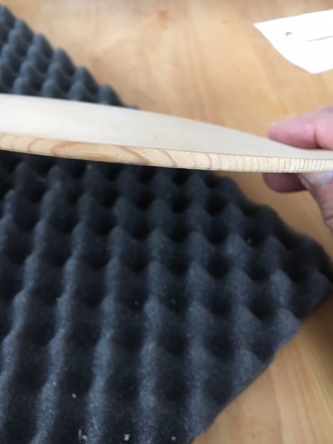 Hand håller ett tunt, ofärdigt fiollock över akustiskt skum med inritade ritsar nära kanten.