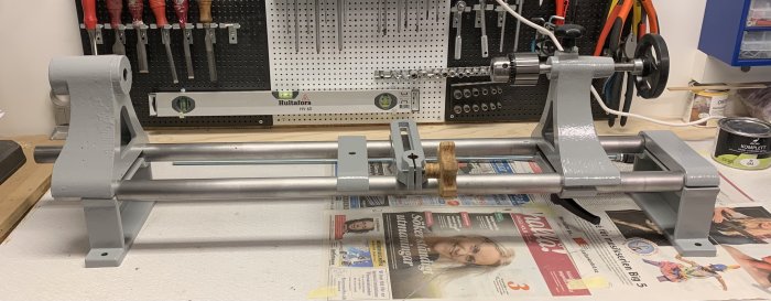 En metallchuckkonstruktion på ett arbetsbord med verktyg i bakgrunden.
