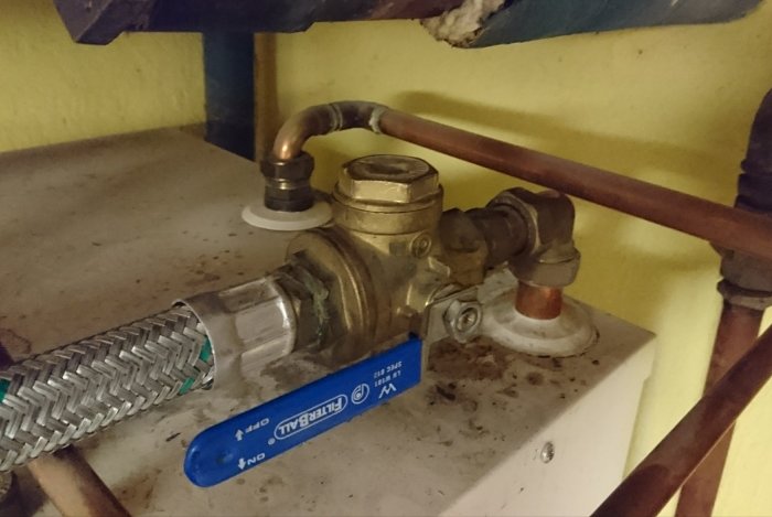 Värmesystemets anslutning med kopparrör och avstängningsventil i ett hus.