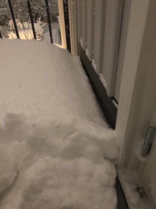 Synligt snöansamling mot altandörrarna på en terrass, risk för vattenskador där vatten läckt in.