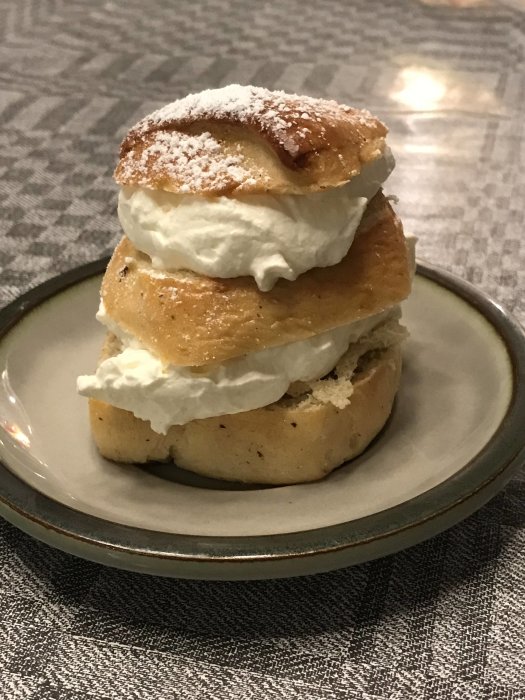 Semla med extra lager grädde och bulle, liknande en Big Mac, på en tallrik.