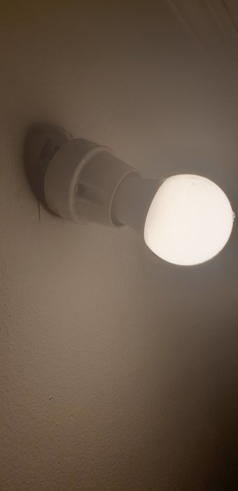 En tänd lampa monterad på vägg i en klädkammare.