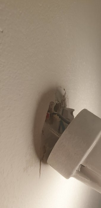Skadad väggfäste till garderob med synliga skruvar och kablar, i behov av reparation eller ersättning.