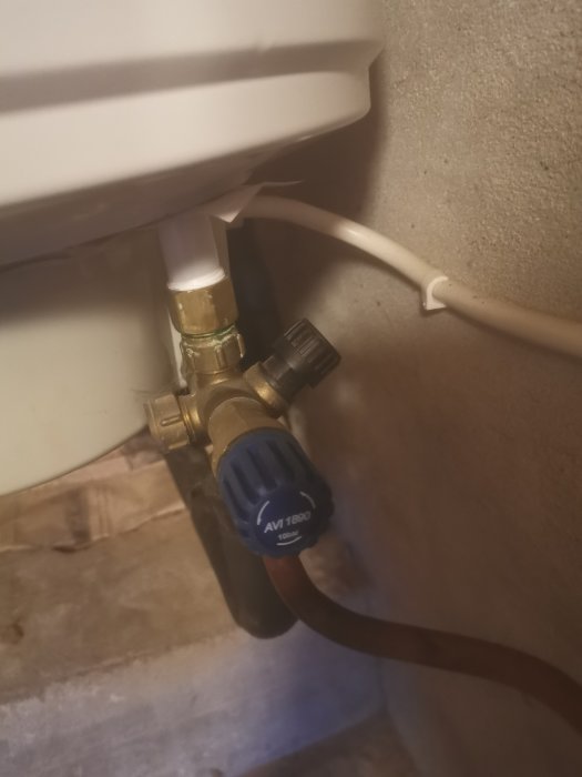 Vattenledning med avstängningsventil och anslutna rör i en källare.