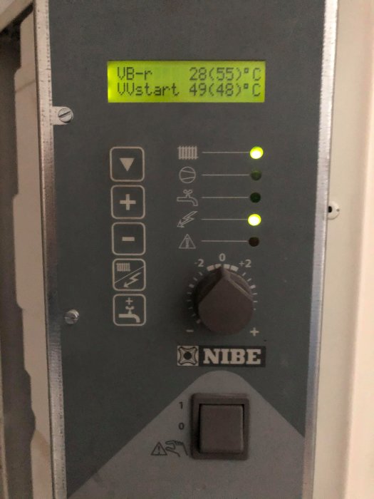 Närbild på en NIBE värmepumps kontrollpanel med display och statuslampor.