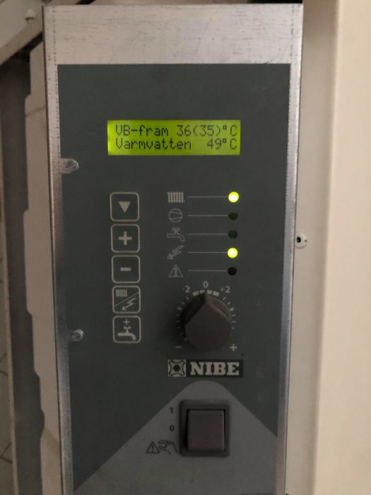 Värmepumpspanel med display som visar temperaturer, varav en är 36,35°C och den andra 49°C, och knappar, märkt NIBE.