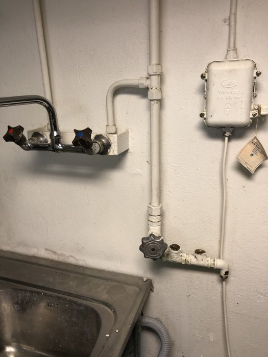 VVS-installation med rör och anslutningar för tvättstuga, inklusive vattenkranar och avstängningsventil.