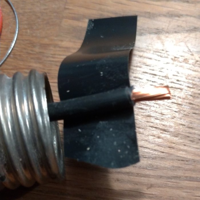 Propphuv med slipad kretskortslaminatbit och eltape på träyta.