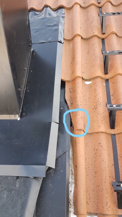 Nyinstallerad skorsten med kamin, uppvisar ett mellanrum mellan takpanna och skorstensbeslag markerat med blå cirkel.