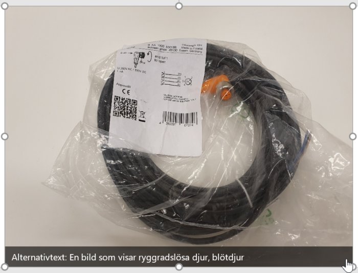 En svart flexibel slang eller kabel i genomskinlig plastförpackning med etikett visande produktdetaljer.
