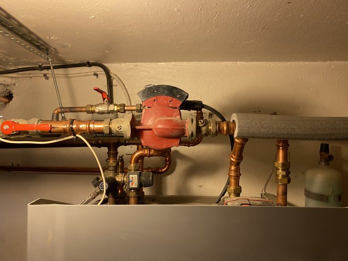 Rörinstallation med radiatorpump, T-kors och termostater som ingår i ett värmesystem.