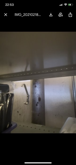 Oskarp bild av metallhyllor i källare med spill och verktyg.