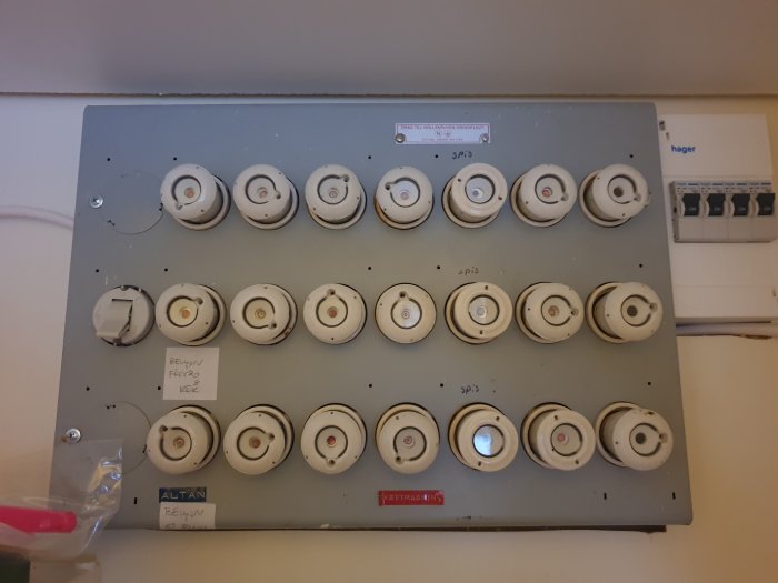 Gammal elcentral med diazedsäkringar och anteckningar, bredvid modern säkringslåda.