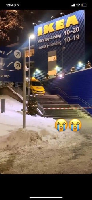 Ambulans fast på en trappa vid IKEA, omgiven av snö på kvällen.