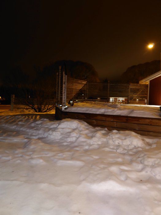 Nattbild av ett snötäckt landskap med grannens katts lysande ögon i mitten.