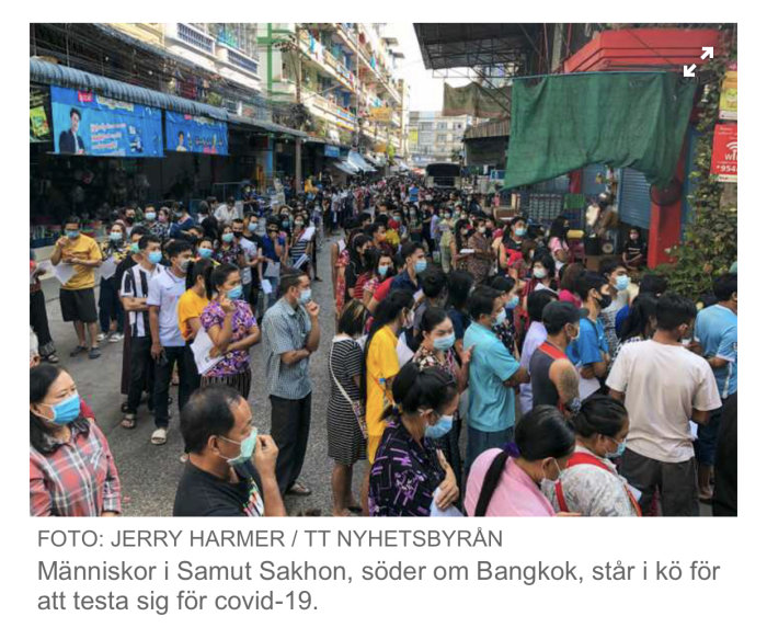 Människor med munskydd står tätt i kö på en gata för att testa sig för covid-19 i Samut Sakhon, Thailand.