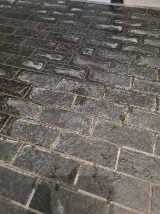 Mörkt klinkergolv i duschen med ljusa fläckar efter rengöringsförsök.