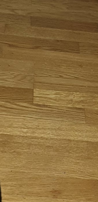 Träparkettgolv med synliga träfibrer och skarvar mellan plankorna.
