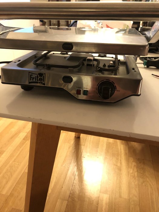 Bordsgrill med termostatvred på ett köksbord, problem med jordad stickpropp nämns.