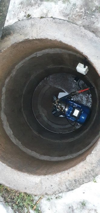 Inuti en brunnskammare med synlig vattenpump och sladdar, frågor om tätning och pumpflytt.
