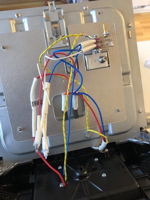 Elektriska kablar i olika färger kopplade till en eldosa, vissa med sockerbitar, i en byggsituation.