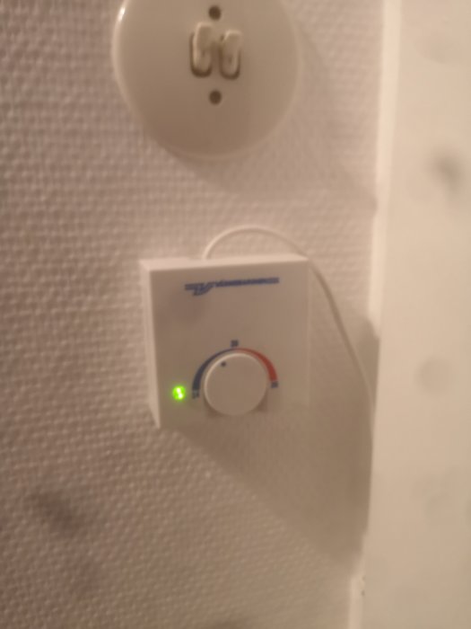 Rumsgivare för pannan monterad på vägg med en grön statuslampa tänd.