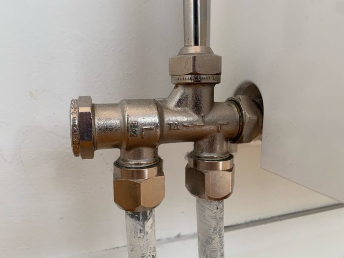 Detaljbild på ett kallt radiatorventil och röranslutningar i ett radhus, inlägget nämner avluftningsförsök och jämförelse med ett varmt element.