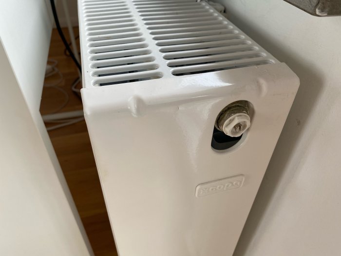 Vit värmeelement i rum, termostat inställd på max, tecken på att den inte blir varm.