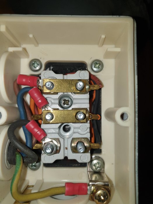 Öppet eluttag med två lösa metallbleck som kopplar samman elkablar, med en öppen plats för ett tredje bleck.