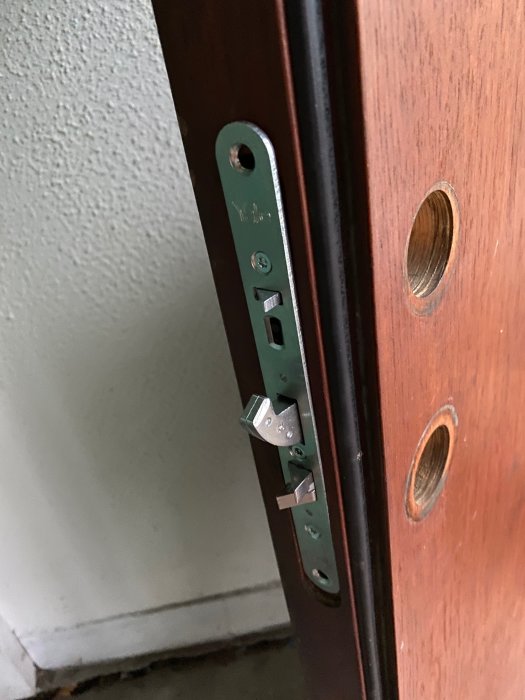 Nyinstallerat låshus i dörrkarm, med bearbetning för passform och tomma hål för trycke och lås.