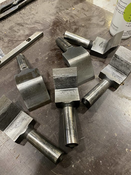 Metallkomponenter som tros vara bakslagskydd och fjädrande knivar för byggprojekt på en arbetsbänk.