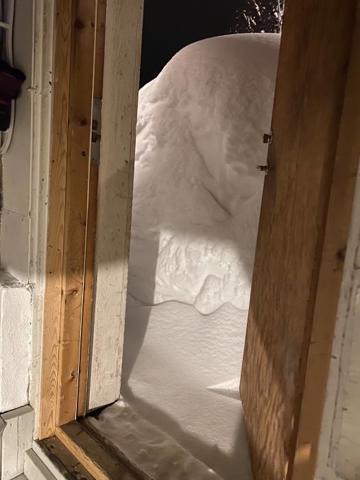 En dörr öppen mot en tjock snödriva som blockerar utgången.