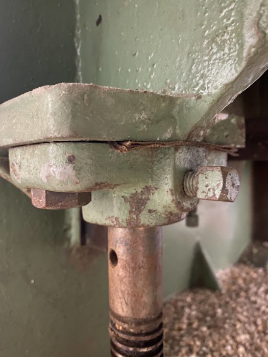 Maskindetalj med korroderade metallshims och bultförband, indikerande möjlig sättning över tid.