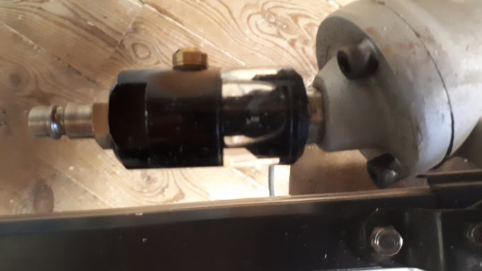 Närbild på en stompicka med dimsmörjare installerad, placerad på ett trägolv.