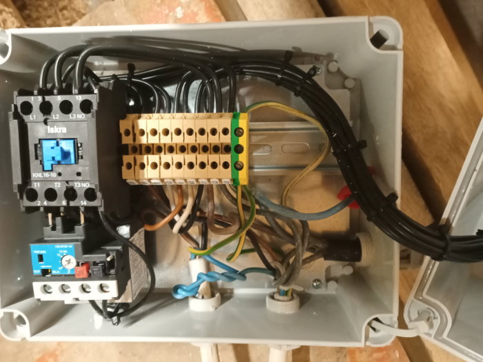 Öppen elcentral med kopplingsplint, kablar och halvautomatisk yd-start för planhyvel, nollan blå ledare ej inkopplad.
