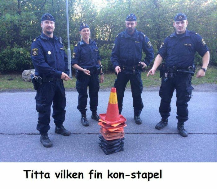 Fyra poliser står bakom en stapel av trafikkoner.