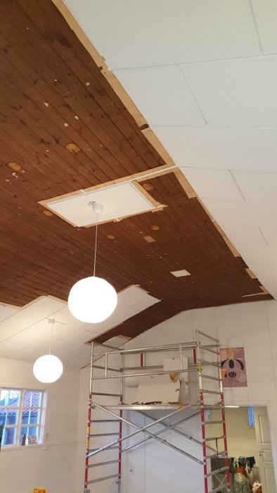 Ett tretex-tak som bågnar och har spruckna brädor i ett äldre missionshus, synligt renoveringsarbete och byggställning.