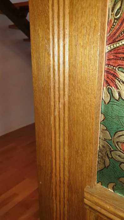 Träpanel med repor och missfärgningar på en dörrlist i ett rum från 1969.