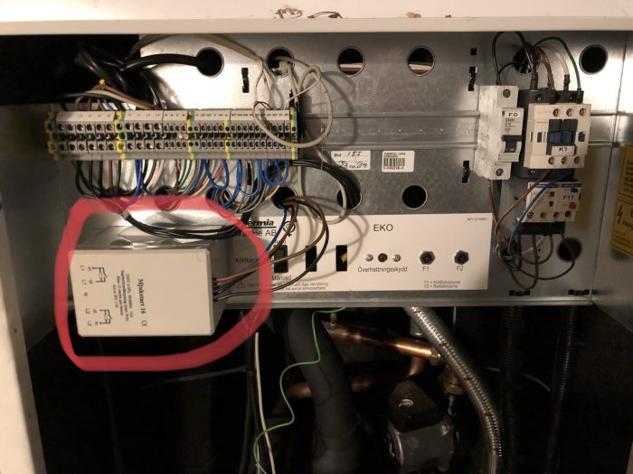 Elcentral med öppen mjukstartlåda, kablar och säkringskomponenter, markerad med röd cirkel.