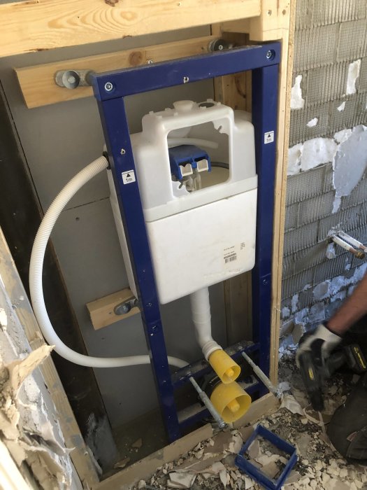 Installation av inbyggt toalettstomme med synliga rester av kakelfix på väggen och golv.