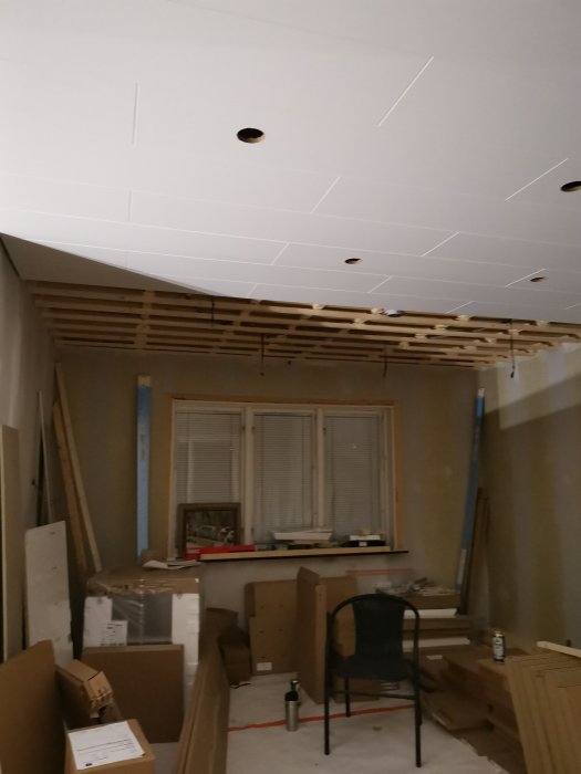 Renoverad hall med nytt tak och förberedelser för belysning bland byggmaterial och verktyg.