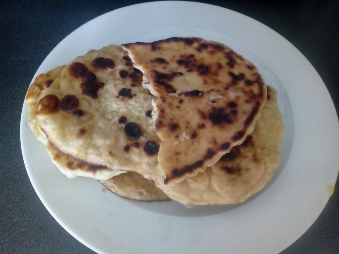Vitlöksnaanbröd med tydliga grillmärken på en vit tallrik.