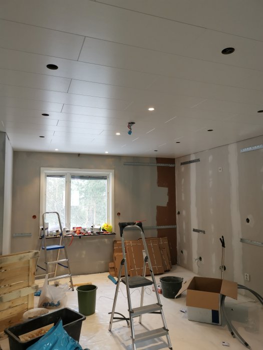 Renoveringsarbete i kök med provisoriskt installerade lampor i taket och renoveringsmaterial synligt.
