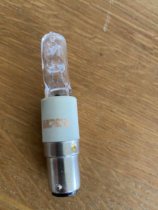 Halogenlampa på träyta med märkningen "18W OSRAM" tydligt synlig på sockeln.