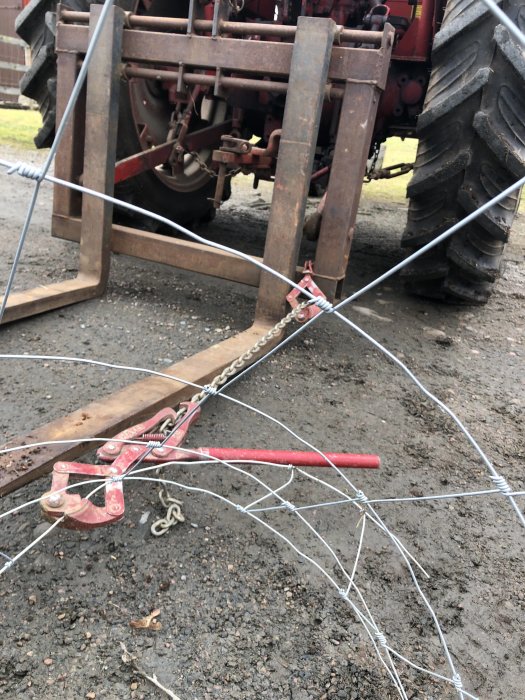 Installation av ett staket med en stolpsträckverktyg framför en traktor, avsett att hålla hundar och barn säkert inne.