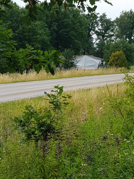 Stort tält uppställt bredvid en väg för byggprojekt under ett uppehåll i regnvädret.