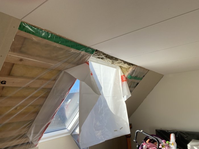Gipsning pågår runt nya takfönster med isolering och plast synlig.
