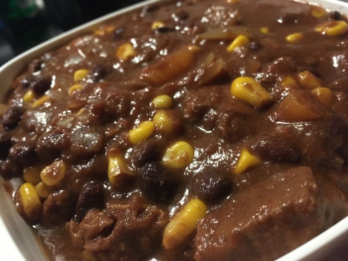 Hemlagad chili med bönor, kött, majs och lök i en maträtt, redo att serveras.